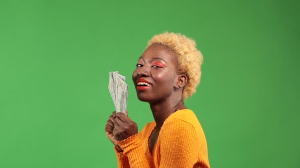 Vacker amerikansk rik kvinna spenderar pengar på värdelös sak, isolerad grön bakgrund. studio skott. — Stockvideo