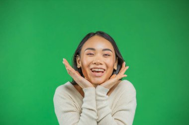 Güzel, Asyalı, mutlu bir kadın, yeşil arka planda, elini tutarak elini tutuyor.