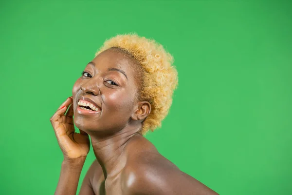 Porträtt av en ung söt leende afrikansk amerikansk kvinna tittar glatt på kameran på grön bakgrund — Stockfoto