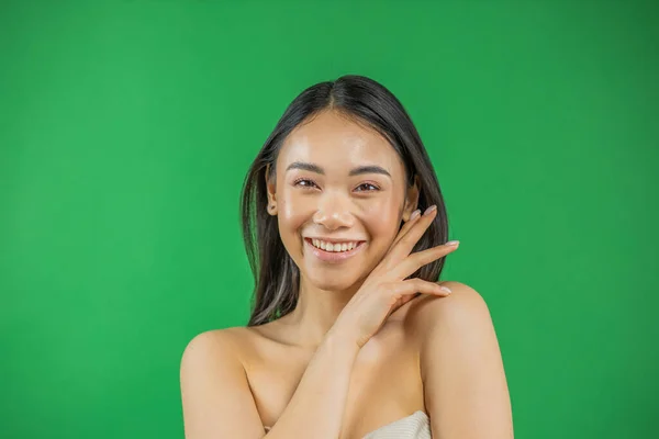 Красивая молодая азиатская женщина улыбается и смотрит в камеру изолированы на зеленом фоне — стоковое фото