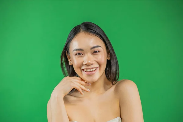 Mulher asiática sorrindo e olhando para a câmera isolada no fundo verde — Fotografia de Stock