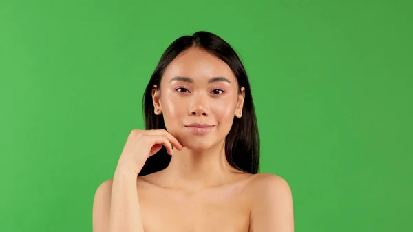 Портрет милой азиатской девушки. Красивая женщина с идеальным макияжем, с голыми плечами на изолированном зеленом фоне — стоковое фото