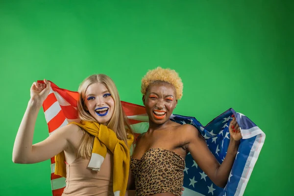 Glada svarta afrikanska och vita vackra sexiga unga glada flickor dansar med flaggan av Amerika i sina händer för att hedra självständighetsdagen på en isolerad bakgrund — Stockfoto