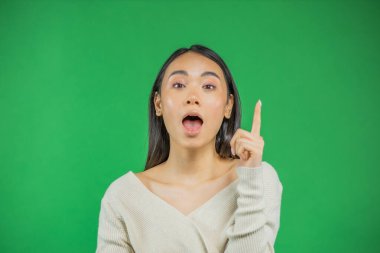 Asyalı genç bir kadın gülümserken işaret ederek fotokopi alanını gösteriyor. Yeşil arka planda izole edilmiş güzel genç iş kadınına yakın çekim