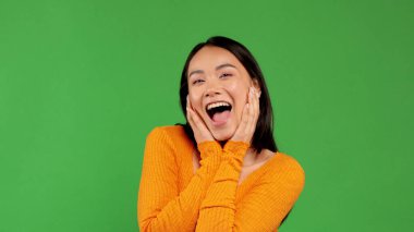 Mutlu Asyalı kadın ağzını açarak yüzünü tutuyor.