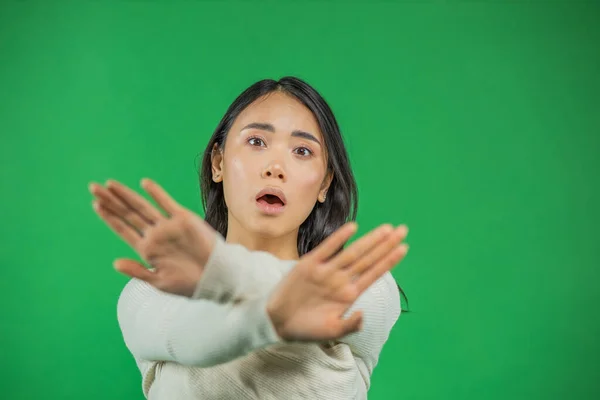 Kızgın ciddi Asyalı kadın yeşil arka planda tek başına dikilirken kollarını kavuşturup kameraya bakıyor. — Stok fotoğraf