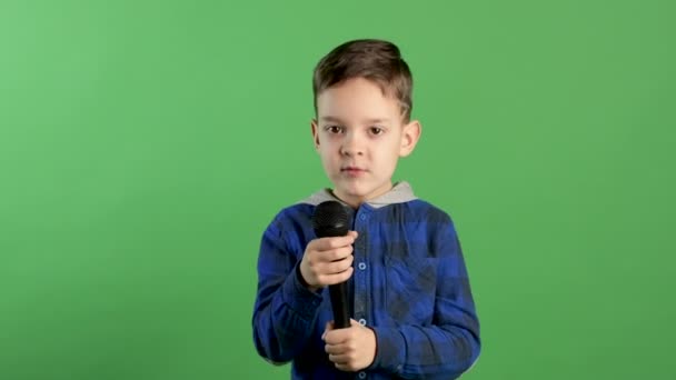 Portrait of boy singing to microphone on green light background, stylish cool guy, entertainment for kids, starting singer — Stock Video