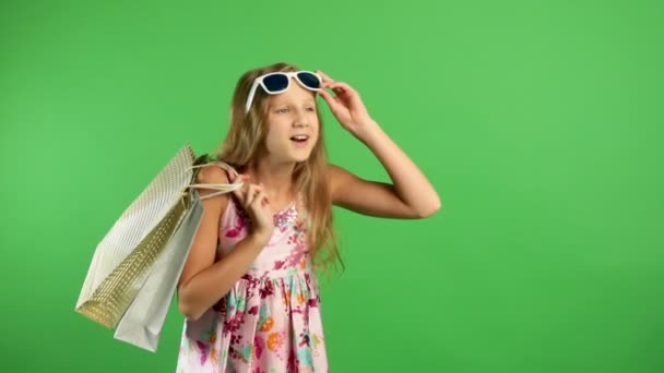 Menina segurando bolsas multicoloridas e caminha sorrindo na tela verde. Compras felizes . — Vídeo de Stock