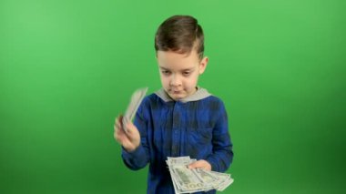 Mutlu çocuk yüz dolarlık banknotları tutuyor ve dağıtıyor. Erken yaştan beri tasarruf ve yatırım kavramı