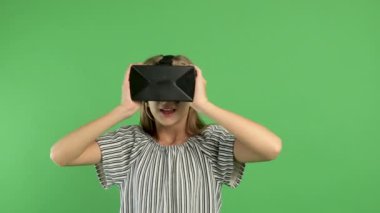 Sevimli genç bir kız interaktif sanal gerçeklik kulaklığı kullanır, şaşırır ve sanal gerçeklikten zevk alır. VR gözlüklü ya da 360 video ya da video oyunu izleyecek bir kasklı. Retro neon ışıklandırma, soyut arkaplan