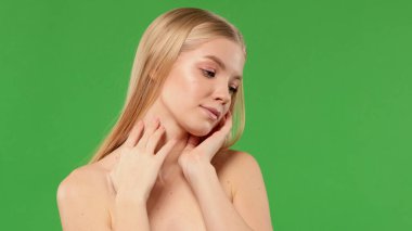 Yeşil arka planda gündüz makyajlı çıplak omuzlu güzel üzgün Avrupalı kadın.