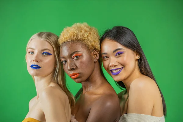 Retrato de belleza de chicas africanas, asiáticas y europeas con hombros desnudos y marca de moda sobre fondo verde. tres hermosas chicas de diferentes razas son blanco y negro con marca natural — Foto de Stock