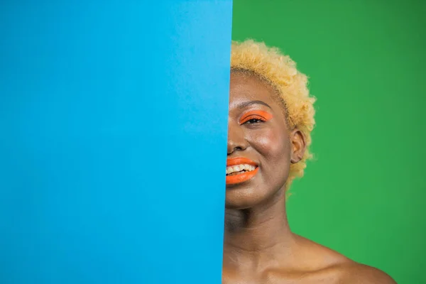 Överraskad afrikansk ung affärskvinna med ljusa make-up, täcker halva ansiktet med tomt papper på grön bakgrund — Stockfoto