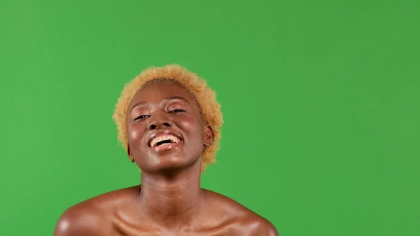 Femme afro-américaine riante avec coiffure afro et bonne humeur, souriante alors qu'elle penche la tête vers l'arrière pour regarder en l'air — Photo