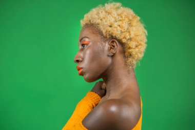 Koyu tenli, güzel bir kadın modelin göz kamaştırıcı portresi. Günlük makyajlı ve romantik dalgalı bir saç stili. Modaya uygun parlak cilt parlatıcısı, seksi dudak parlatıcısı ve koyu kaşlar.