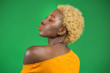 Güzel, şehvetli, genç, Afro-Amerikalı bir kadın omzuna dokunuyor ve yarı yarıya geyik arka planında duruyor.