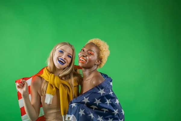 Svart kvinna med blond amerikansk blond kvinna kramas hålla amerikansk flagga och leende, begreppet oberoende kvinnor i Amerika och självständighetsdagen i Amerika — Stockfoto