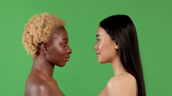 Gros plan portrait de beauté de jeune femme afro-américaine et femme asiatique à la peau lisse et saine se regardant et souriant sur fond vert. Concept de santé des femmes — Photo