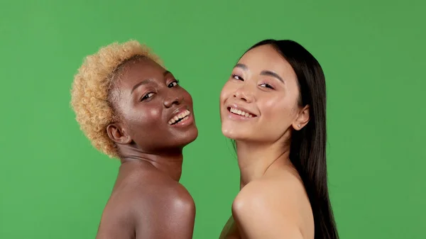 Begrepp skönhet, kroppsvård och människor - vackra leende unga kvinnor med bara axlar över grön bakgrund — Stockfoto