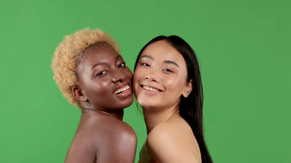 Vacker svart kvinna med afro hår och ganska asiatisk kvinna som har roligt leende och dans i studio på grön bakgrund — Stockfoto