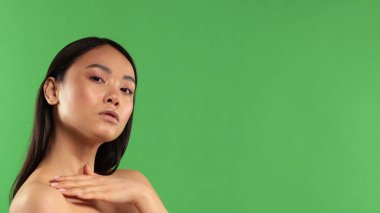 Asyalı kız stüdyoda yeşil arka planda el ele tutuşuyor.