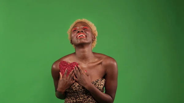 Attrayant souriant afro-américain femme isolée sur fond vert avec coeur rouge — Photo