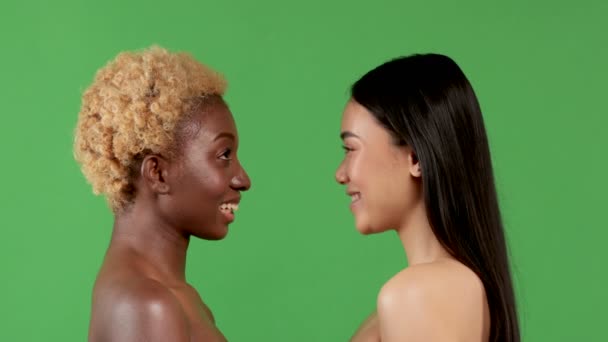 4K Pouting, un retrato de dos chicas de perfil mirándose. Mujer afroamericana y china y fondo verde aislado — Vídeo de stock