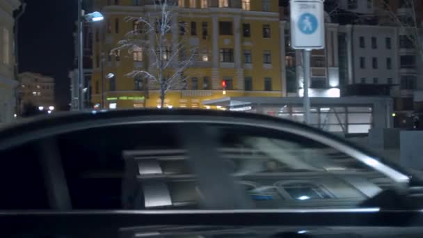 Nattstad genom sidofönstret på en bil i rörelse — Stockvideo