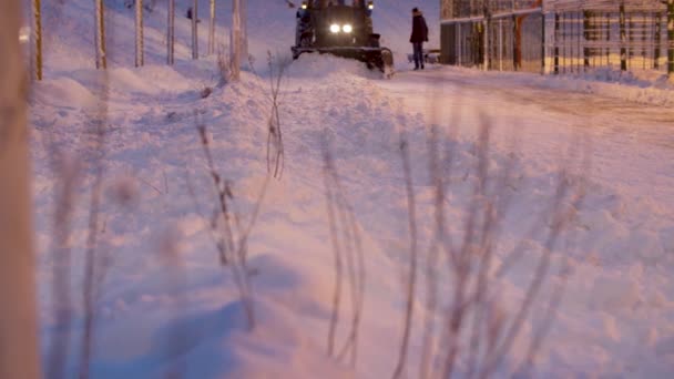 拖拉机修整师把雪从积雪覆盖的公园里的路上移开 前灯上的雪亮得很美 工作中的道路服务 — 图库视频影像