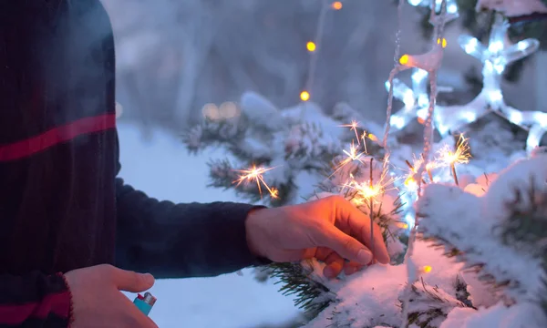 Mannelijke hand stichtend brand naar sterretjes op een kerstboom — Stockfoto