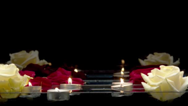 Gros plan de bougies et de roses qui flottent sur l'eau sur un fond noir 