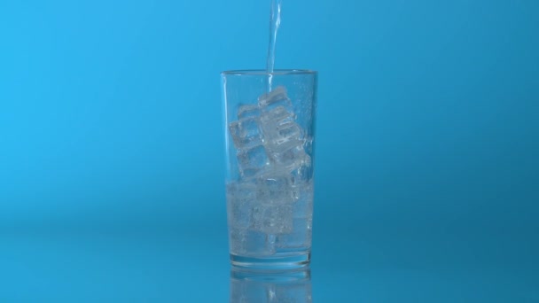 Nahaufnahme Mineralwasser Das Ein Glas Mit Eis Auf Blauem Hintergrund — Stockvideo