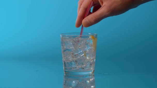 Κοντινό Χέρι Ανάμιξη Νερού Ένα Ποτήρι Μπλε Φόντο Φυσικό Ανθρακούχο — Αρχείο Βίντεο