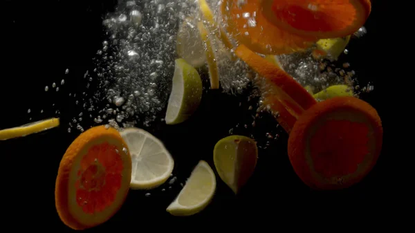 Dilimlenmiş limon ve portakallar suya düşüyor.