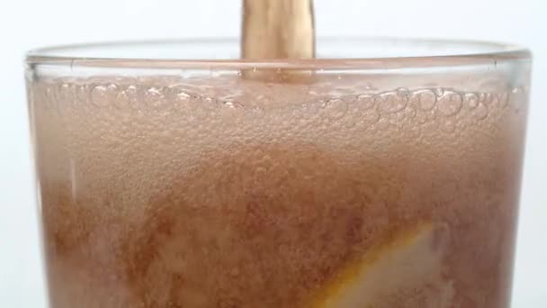 一股可乐倒入杯子里 泡沫上升 冰块和一片柠檬出现在美味饮料的表面 焦炭在白色背景上慢动作宏观射击 — 图库视频影像