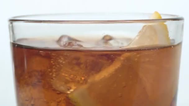 Ice cubes and lemon slice in the glass of cola — Stock Video