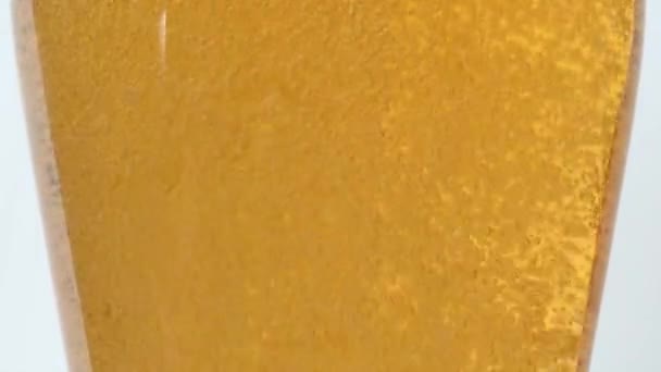 将啤酒倒入透明的玻璃杯中 侧视角度低 运动缓慢 背景洁白 浮出水面的气泡 — 图库视频影像