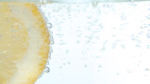 巨无霸在白底矿泉水里切柠檬片 玻璃中的天然碳化矿泉水 慢动作中的气泡 — 图库视频影像