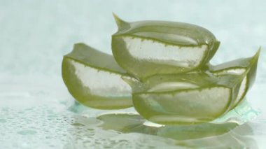 Dilimlenmiş aloe vera yapraklarını beyaz arka planda meyve suyu damlacıklarıyla kapatın. Yavaş çekim