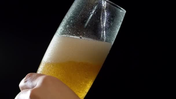 黒を背景に瓶から注ぐビールを誤ってガラスに閉じます 泡が立ち上がって 美しく光の線に輝いています クラフトビールの店から — ストック動画