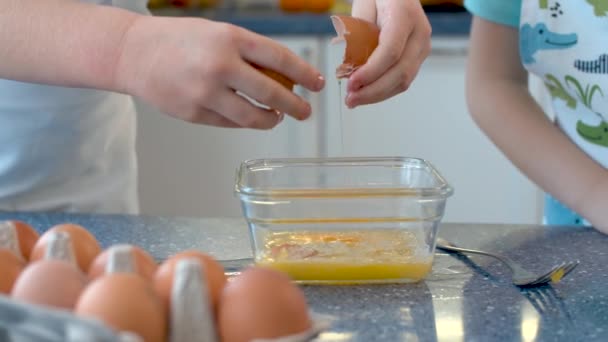 把孩子们的手放在明亮的厨房里做糕点 一个把鸡蛋打成玻璃碗 另一个把糖倒在那里 慢动作 — 图库视频影像