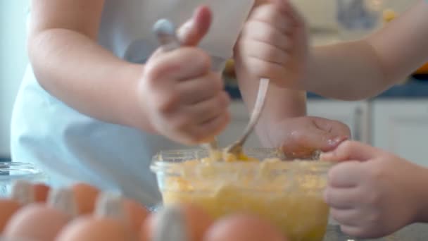 两个孩子的手把黄油和糖、蛋混合在一起 — 图库视频影像