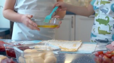 Pizza pişiren iki genç şefin ellerini kapat. Elinde kahve kasesi olan bir kız ve fırça kullanarak hamuru yuvarlayan bir oğlan..