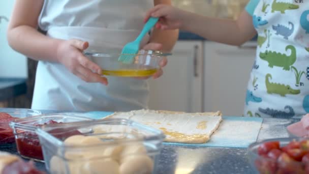 两个烹饪披萨的年轻厨师手拉手 一个拿着面团碗的女孩和一个拿面团盖住面团的男孩 用炊具刷子 — 图库视频影像