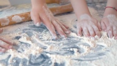 Four childrens hands playing with flour