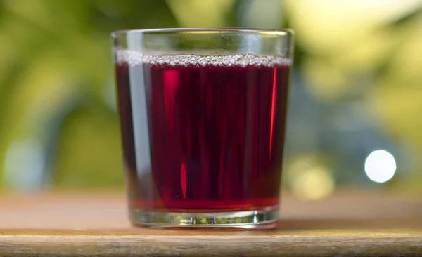 红色透明的果汁或葡萄酒在玻璃中的天然绿色背景 关闭樱桃或石榴或越橘果汁或葡萄酒 健康饮食概念 — 图库照片