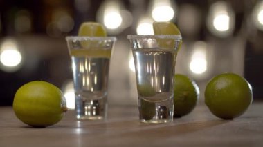 İki bardağı yanan tekilayla kapat. Sert alkollü içki ve limonlu Stemware. Bulanık ampullerin arkaplanındaki çubuk sayacı.