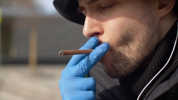 Человек курит в защитных перчатках — стоковое видео