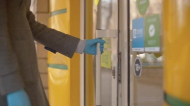 Kapıyı açan koruyucu eldivenli kadın.