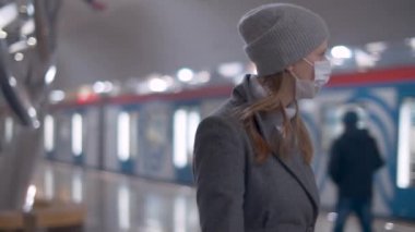 Maskeli kadın metro istasyonunda yürüyor.